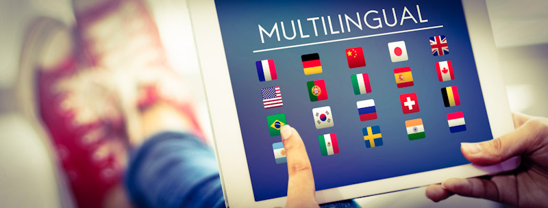 Girl is choosing a language on a tablet represented by several flags.